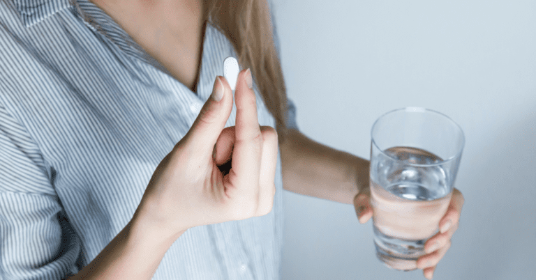 Woman taking a pill with a glass of water