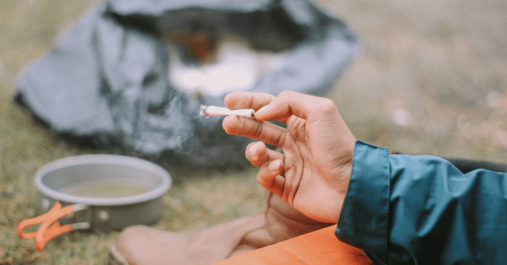 A person's hand holding a cigarette