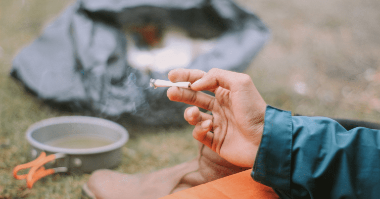 A person's hand holding a cigarette