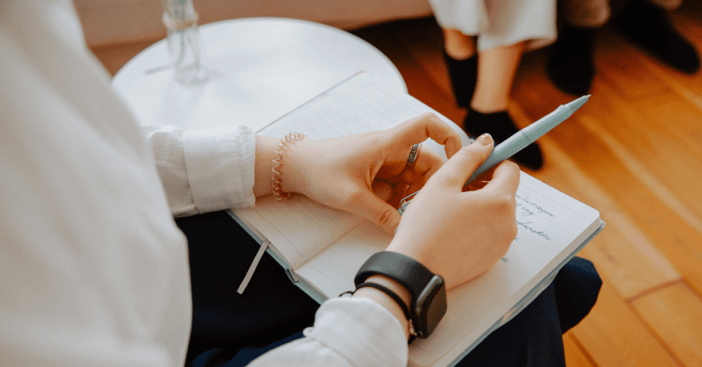 Person holding a notebook with a pen in their hand 