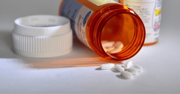 Orange pill bottle with pills spilling out on the counter
