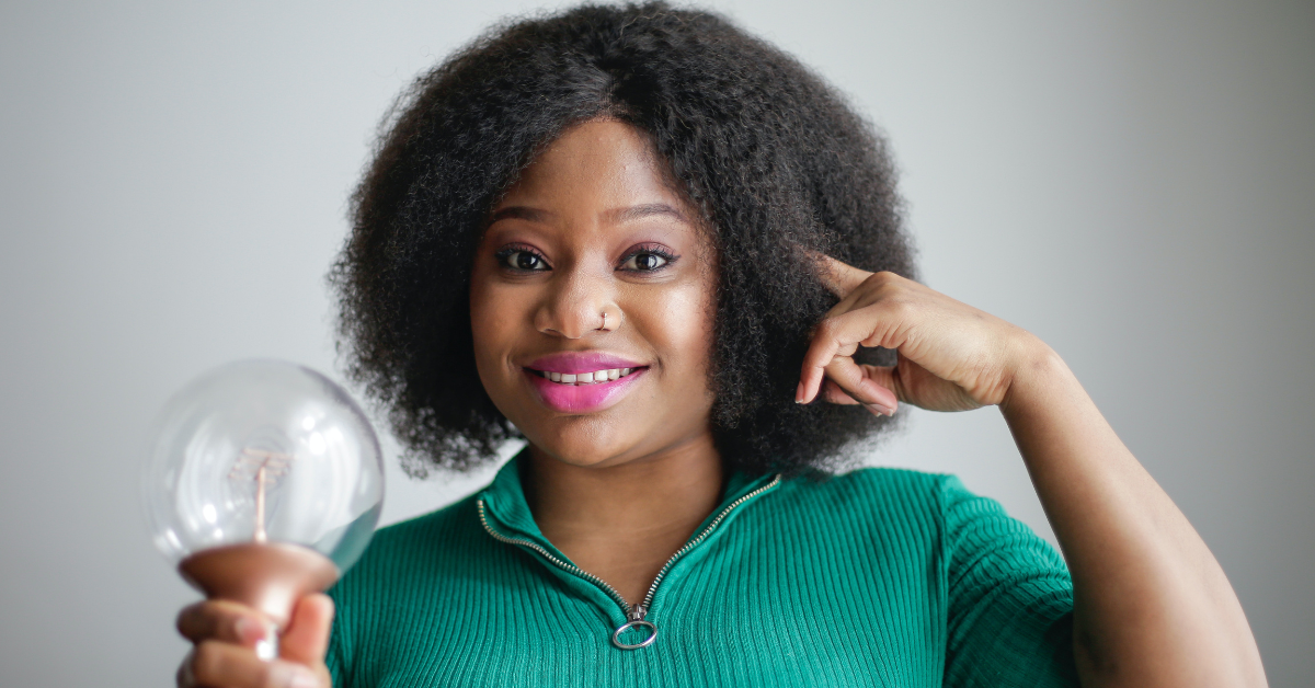 Woman holding a lightbulb pointing to her ear