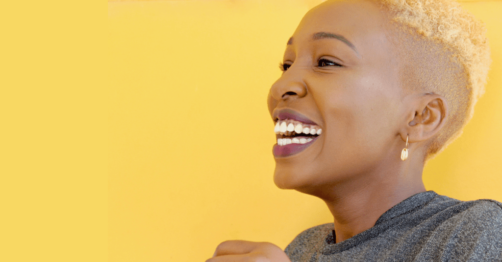 Woman smiling in front of a yellow background