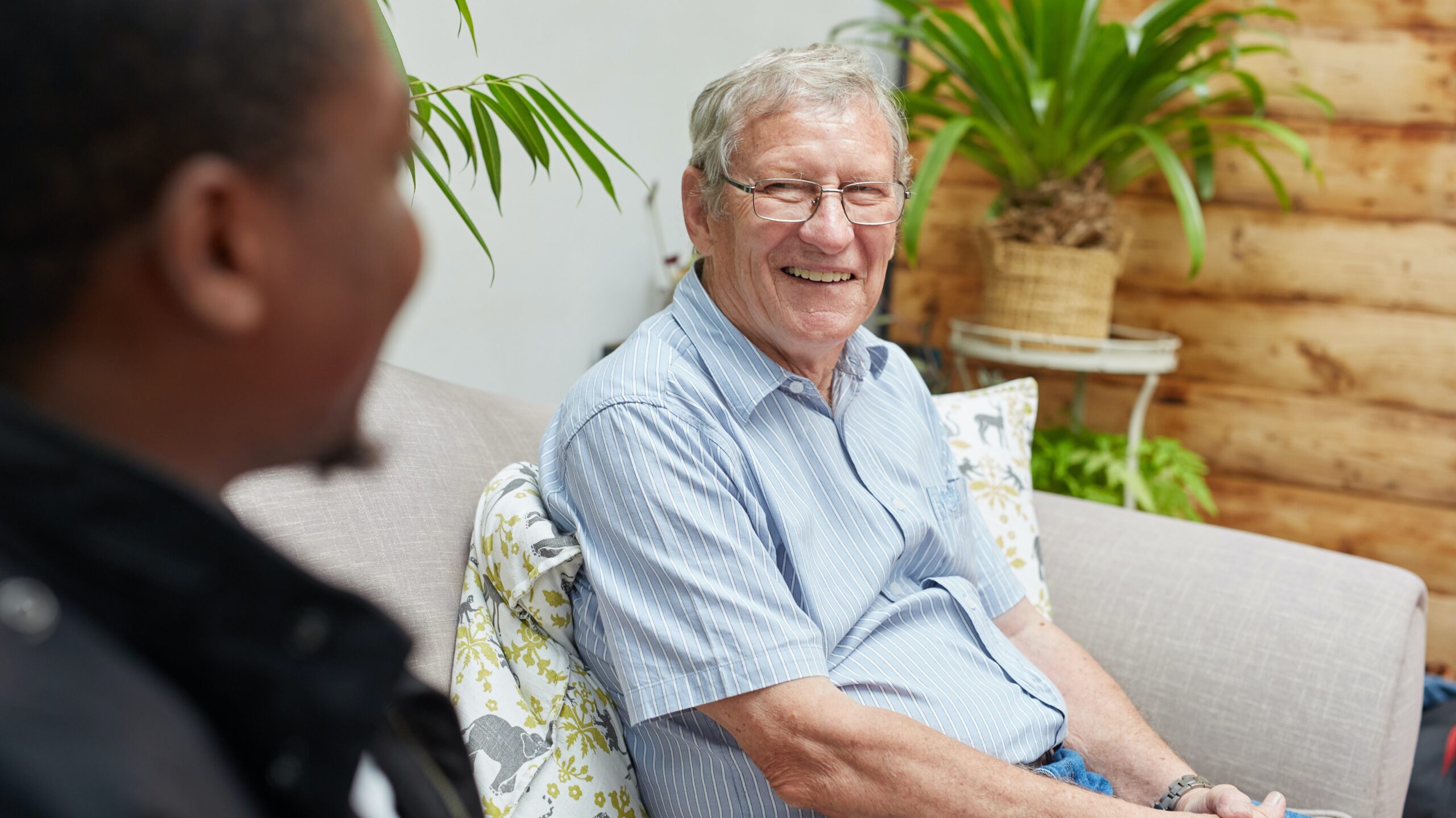 Older man sitting on the couch across from someone