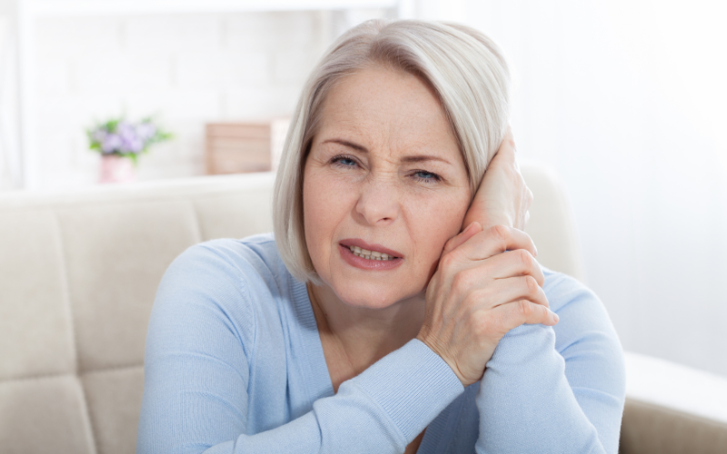 Woman with tinnitus holding her ear in pain