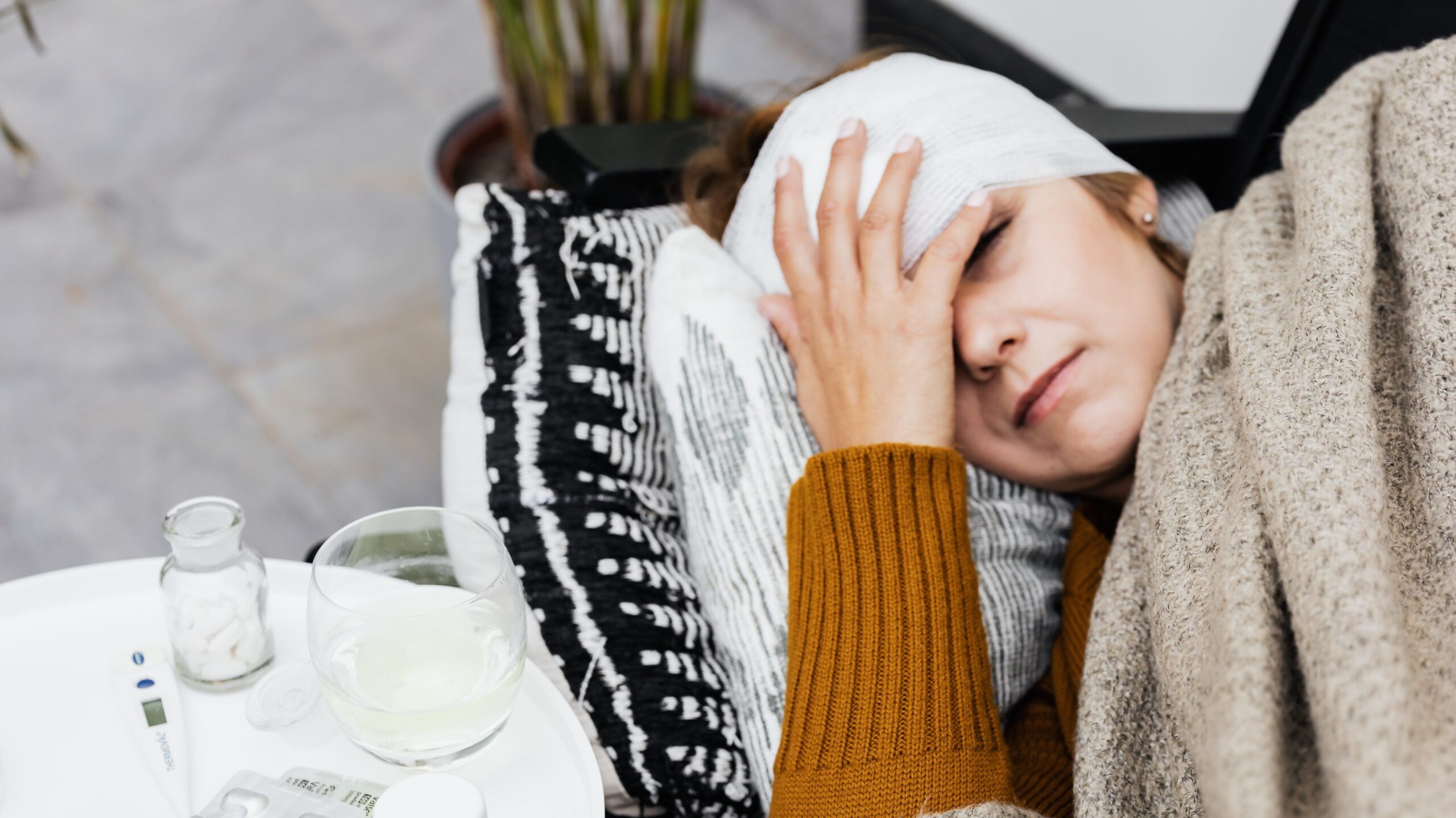 Sick woman laying down with a bandage over her forehead