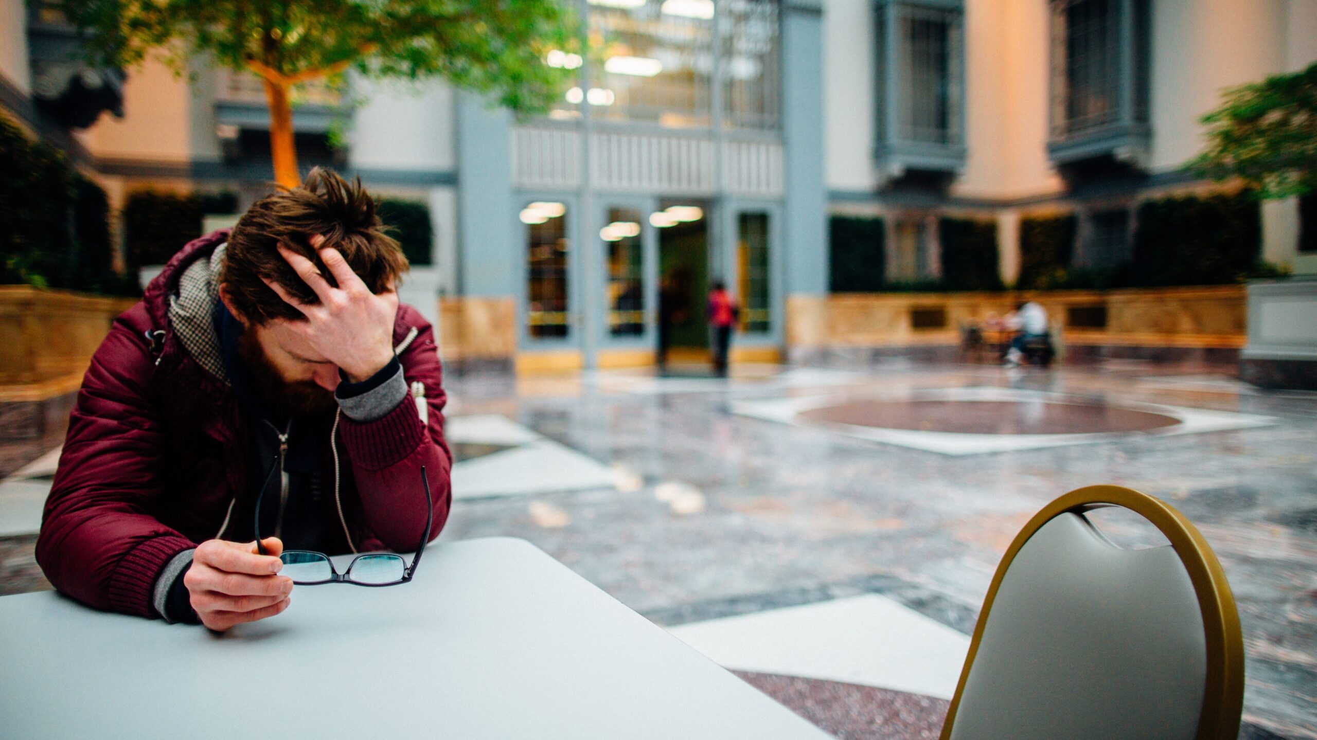 Man sitting at a table with his hand holding his head up