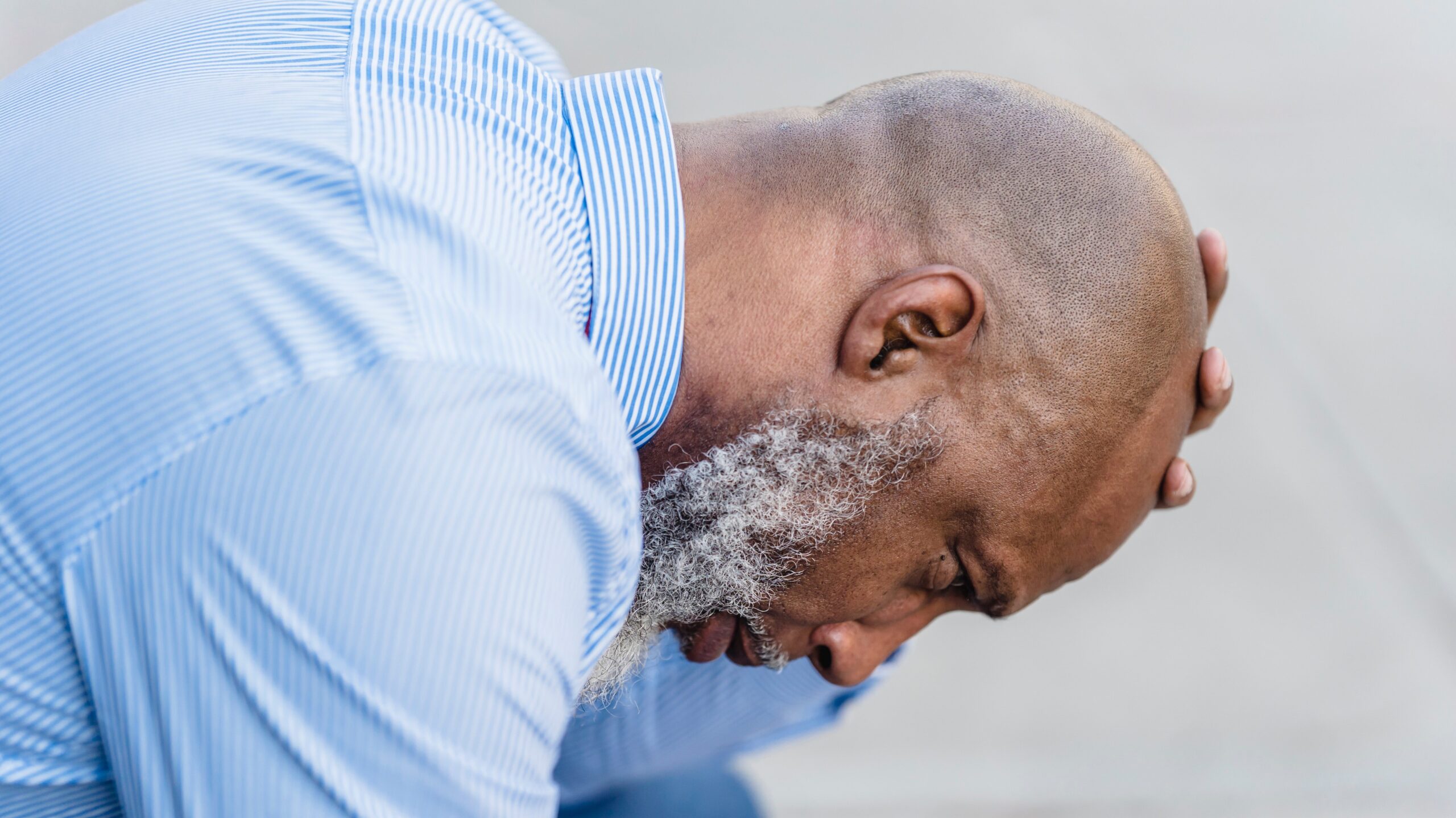 Man sitting down holding his head in his hand