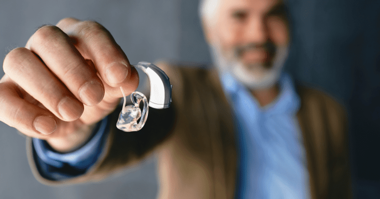 Man holding up hearing aids