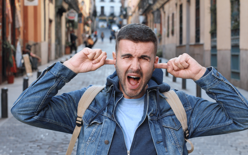 Man with his fingers in his ears to block out loud sounds