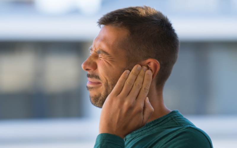 Man with tinnitus holding his ear in pain