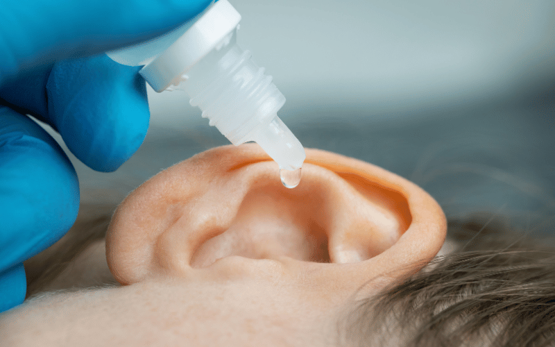 Person putting ear drops into their ears