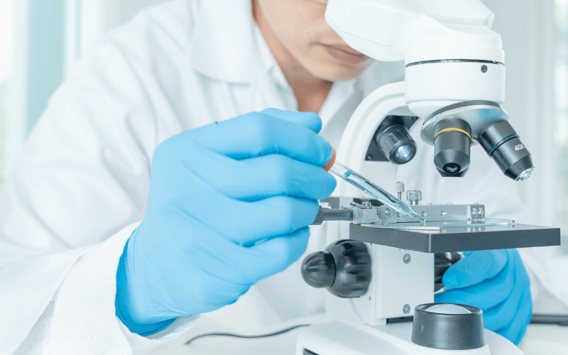 Researcher testing samples under a microscope