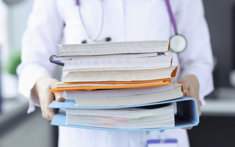 A doctor holding a stack of medical journals