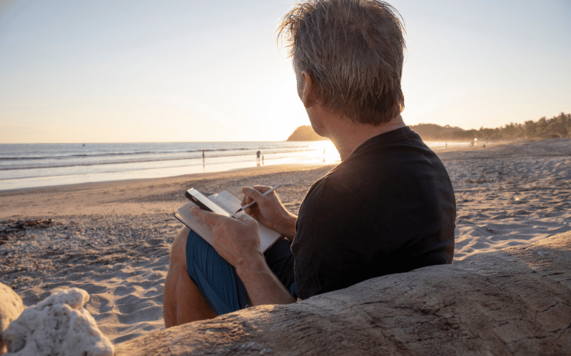 Man sitting on the beach while gratitude journaling